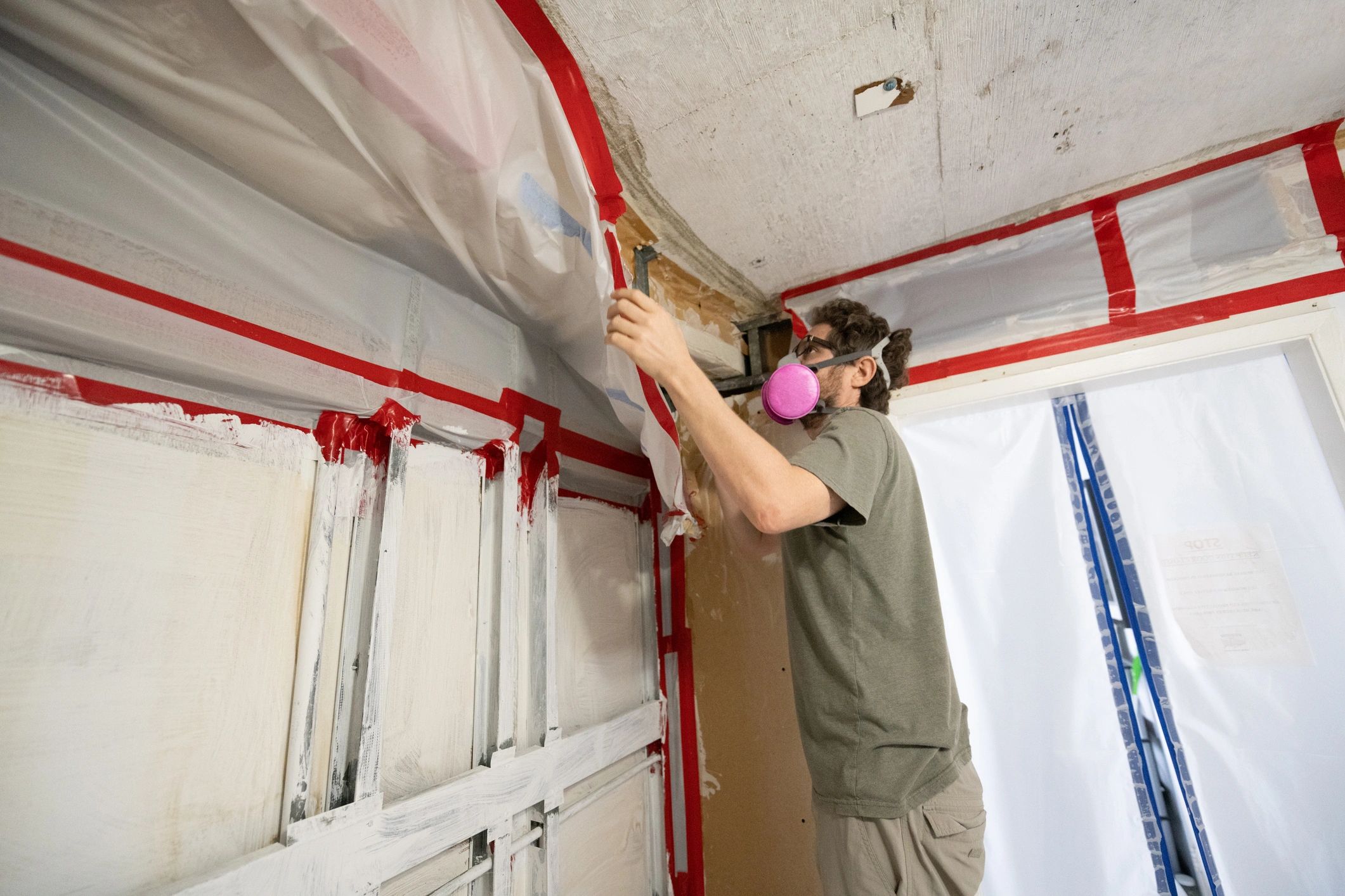 Man Wearing Respirator Inspects Home Construction Site after Mold Remediation