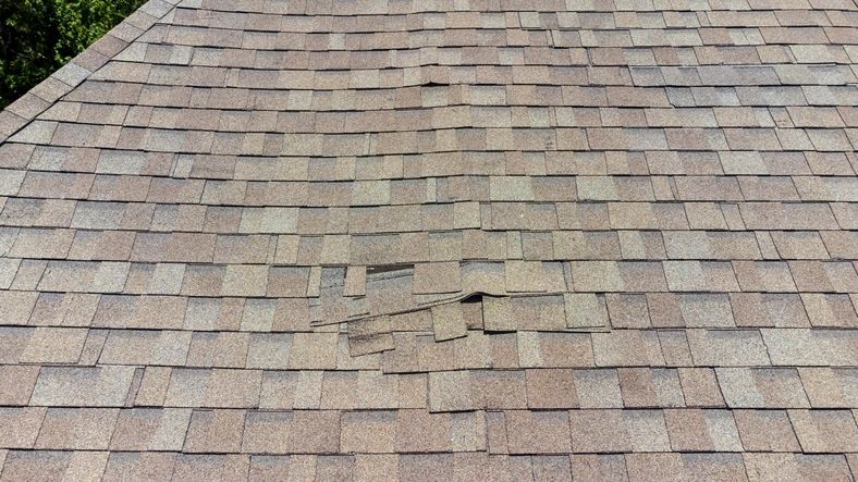 Storm-damaged roof shingles on Arizona home needing emergency protection