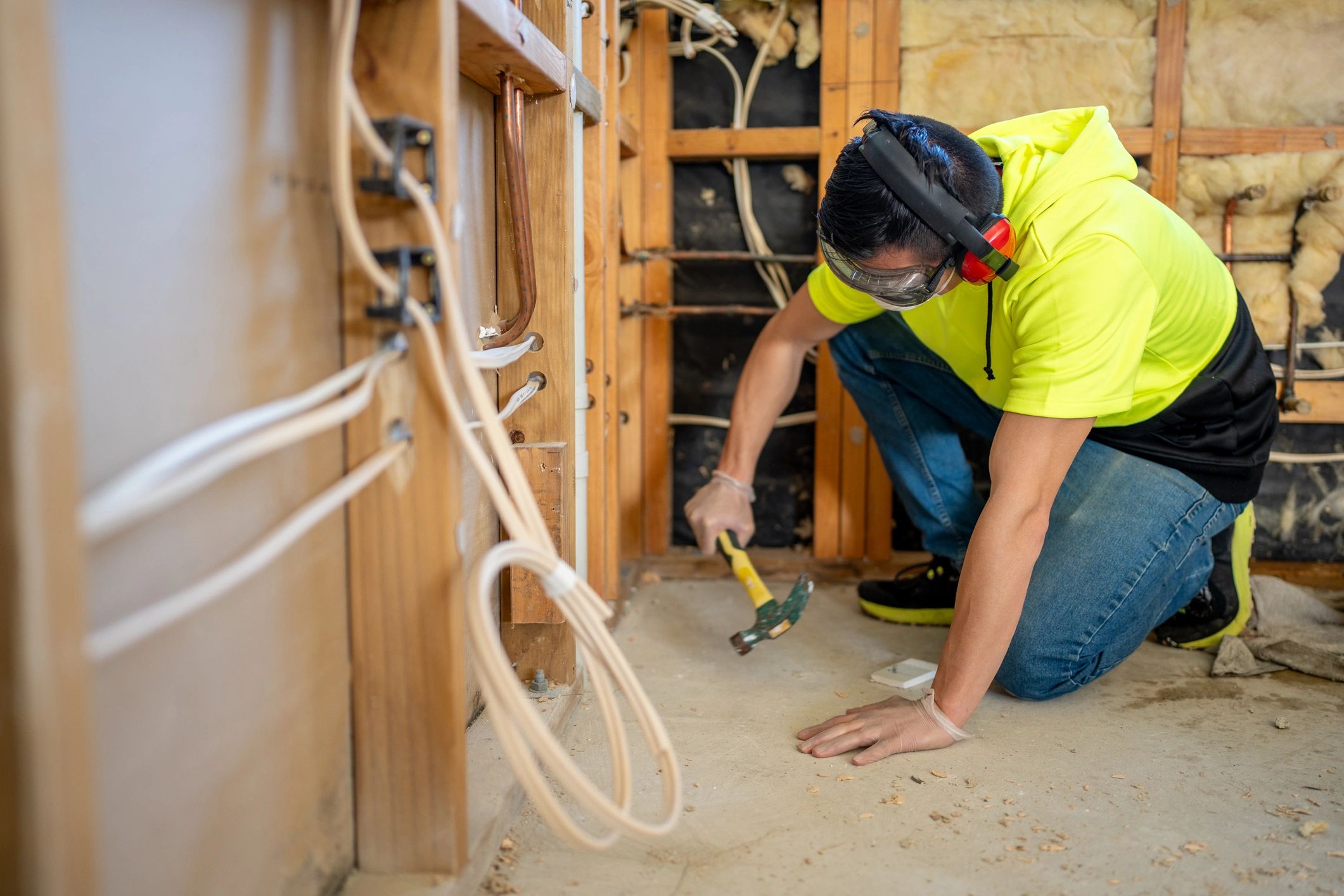 Worker hammering floor fasteners during renovation